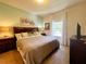 This bedroom offers a queen bed, two nightstands, an entertainment center, and a sun-filled window with white drapes at 5356 Diplomat Ct # 108, Kissimmee, FL 34746
