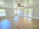 Open concept living room with wood-style floors, a ceiling fan, and a set of glass doors at 5704 Ansley Way, Mount Dora, FL 32757