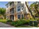 Condo building showcasing tan and white exterior, with screened in balconies and lush landscaping at 6214 Stevenson Dr # 106, Orlando, FL 32835