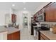Cozy kitchen features stainless steel appliances and laminate flooring, flowing into hall to rooms beyond at 7144 Five Oaks Dr, Harmony, FL 34773