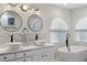 Bright bathroom featuring double vessel sinks, stylish fixtures, and a modern soaking tub beneath arched windows at 7222 Stanford Dr, Lakeland, FL 33809