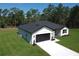 Aerial view of a modern home with a well-kept lawn, dark roof, attached garage, and concrete driveway at 814 Gator Ln, Deltona, FL 32738