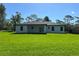 Well-maintained home featuring a back patio, lush green lawn, and a dark roof at 814 Gator Ln, Deltona, FL 32738