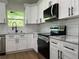 Modern kitchen featuring white cabinetry, subway tile backsplash, granite countertops, and stainless steel appliances at 814 Gator Ln, Deltona, FL 32738
