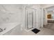 Bright bathroom features a glass-enclosed shower, soaking tub, marble-look tile and wooden vanity at 9055 Treasure Trove Ln # 409, Kissimmee, FL 34747