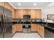 Well-lit kitchen featuring stainless steel appliances, wood cabinets, and dark countertops with tile floor at 9055 Treasure Trove Ln # 409, Kissimmee, FL 34747