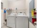Functional laundry room with side-by-side washer and dryer and convenient overhead shelving and fire extinguisher at 9055 Treasure Trove Ln # 409, Kissimmee, FL 34747