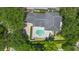 Stunning aerial view of the home featuring a backyard pool, patio, and lush landscaping with mature trees at 9799 Covent Garden Dr, Orlando, FL 32827
