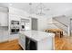 Modern white kitchen with island including wine fridge, stainless appliances, marble countertops, and eat-in table at 9799 Covent Garden Dr, Orlando, FL 32827