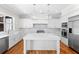A modern white kitchen featuring an island, stainless steel appliances, and marble countertops and backsplash at 9799 Covent Garden Dr, Orlando, FL 32827
