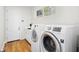 Bright laundry room with a modern washer and dryer set, wooden floors, and ample cabinet space at 9799 Covent Garden Dr, Orlando, FL 32827