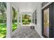 Covered patio with stone floors and pillars, overlooking the manicured front yard with trimmed bushes at 9799 Covent Garden Dr, Orlando, FL 32827