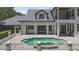 Backyard pool and spa surrounded by a stone patio and manicured landscaping with white pillars at 9799 Covent Garden Dr, Orlando, FL 32827
