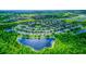 Panoramic aerial view of a lush residential community surrounding a tranquil lake with a fountain feature at 12715 Moss Park Ridge Dr, Orlando, FL 32832