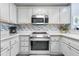 Bright kitchen with stainless steel appliances, white cabinets, and modern backsplash at 13415 Blue Heron Beach Dr # 401, Orlando, FL 32821