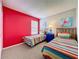 Bright bedroom featuring two twin beds with colorful striped bedding and red accent wall at 1426 Park Park, Haines City, FL 33844