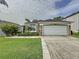 Well-maintained single-story home with a two-car garage and a lush front lawn with tropical landscaping at 1428 Park Pl, Haines City, FL 33844