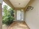 Cozy front porch featuring a white door with sidelight, decorative metal art and mature landscaping at 1428 Park Pl, Haines City, FL 33844