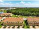 Aerial view of townhomes with terra cotta roofs, garages, paver driveways, green space and a pond in the background at 14344 Swanley St, Orlando, FL 32832