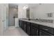 A bathroom featuring double sinks, granite countertops, dark cabinetry, and a spacious glass enclosed walk-in shower at 14344 Swanley St, Orlando, FL 32832