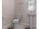 Well-lit powder room features a pedestal sink, toilet and stylish oval mirror at 14344 Swanley St, Orlando, FL 32832