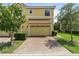 A two-story yellow townhome featuring a red tiled roof, a two-car garage, and a brick driveway at 14344 Swanley St, Orlando, FL 32832