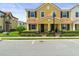 A two-story yellow townhome featuring a red-tiled roof, black shutters, and manicured landscaping at 14344 Swanley St, Orlando, FL 32832