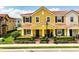 A two-story yellow townhome featuring a red tiled roof, black shutters, and manicured landscaping at 14344 Swanley St, Orlando, FL 32832