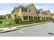A row of two-story yellow townhomes featuring red tiled roofs, black shutters, and manicured landscaping at 14344 Swanley St, Orlando, FL 32832