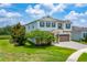 Two-story home with a two-car garage, green shutters, mature trees, and a brick paved driveway at 14421 Ward Rd, Orlando, FL 32824