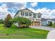 Two-story home with a two-car garage, green shutters, mature trees, and a brick paved driveway at 14421 Ward Rd, Orlando, FL 32824