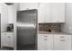 Bright kitchen showing white cabinets, stainless steel refrigerator, and mosaic tile backsplash at 14421 Ward Rd, Orlando, FL 32824