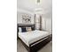 A bedroom featuring a queen-sized bed with an overhead light, painting and framed window at 1456 Belle Terre Rd, Davenport, FL 33896
