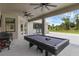 Spacious outdoor living area with a covered patio, ceiling fans, and a pool table for entertaining at 1504 Cordgrass Way, Lakeland, FL 33813