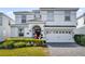 Charming two-story home with a well-manicured lawn, white garage door, and lovely front yard greenery at 1560 Maidstone Ct, Davenport, FL 33896