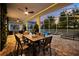 Inviting outdoor dining area with a table, seating, and string lights overlooking the pool and beautifully landscaped backyard at 1560 Maidstone Ct, Davenport, FL 33896