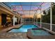 Inviting screened-in pool and spa with poolside seating and lush vertical garden accents at 1560 Maidstone Ct, Davenport, FL 33896