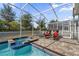 Relaxing poolside view featuring a spa and lounge chairs in the screened patio with a view of the backyard at 1560 Maidstone Ct, Davenport, FL 33896