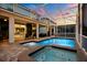 Sparkling pool and jacuzzi in a screened lanai with views of the home's exterior and lush landscaping at 1560 Maidstone Ct, Davenport, FL 33896