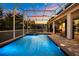 Beautiful pool and spa area with string lights, screened enclosure, and lush landscaping creating a relaxing outdoor oasis at 1560 Maidstone Ct, Davenport, FL 33896