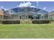 Backyard view of home with screened in patio and golf course in the distance at 1590 The Oaks Blvd, Kissimmee, FL 34746