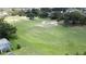 Overhead view of green grass, mature landscaping, and a golf course in the background at 1590 The Oaks Blvd, Kissimmee, FL 34746