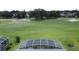 The backyard has green grass, mature landscaping, with view of a golf course and screened-in pool at 1590 The Oaks Blvd, Kissimmee, FL 34746