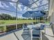 Screened patio with golf course views, featuring an umbrella table and seating at 1590 The Oaks Blvd, Kissimmee, FL 34746