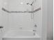 Bright bathtub and shower in the bathroom with neutral tile surround and modern fixtures at 168 Jensen Dr, Groveland, FL 34736