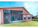 Rear exterior view of house featuring screened lanai, sunroom, windows, and large lawn at 233 Rialto Rd, Kissimmee, FL 34759