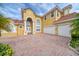 Beautiful two-story home featuring a brick driveway, three-car garage, and arched entryway at 2333 Pinehurst Ct, Davenport, FL 33837