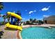 The fun pool area features a blue and yellow water slide, lounge chairs, and nearby palm trees at 2333 Pinehurst Ct, Davenport, FL 33837