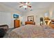 Cozy main bedroom with ceiling fan, television, wooden furniture, and an adjacent ensuite bathroom at 3193 Whispering Trails Ave, Winter Haven, FL 33884