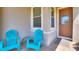 Inviting front porch with tiled flooring, two bright blue Adirondack chairs, and a stylish glass-paneled front door at 328 Toldedo Rd, Davenport, FL 33837